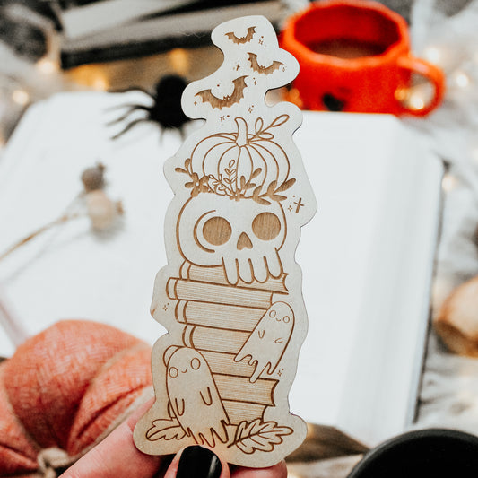 Spooky Cute Halloween bookmark made from wood, engraved with a haunted bookstack featuring a skull, pumpkin, ghosts and bat design