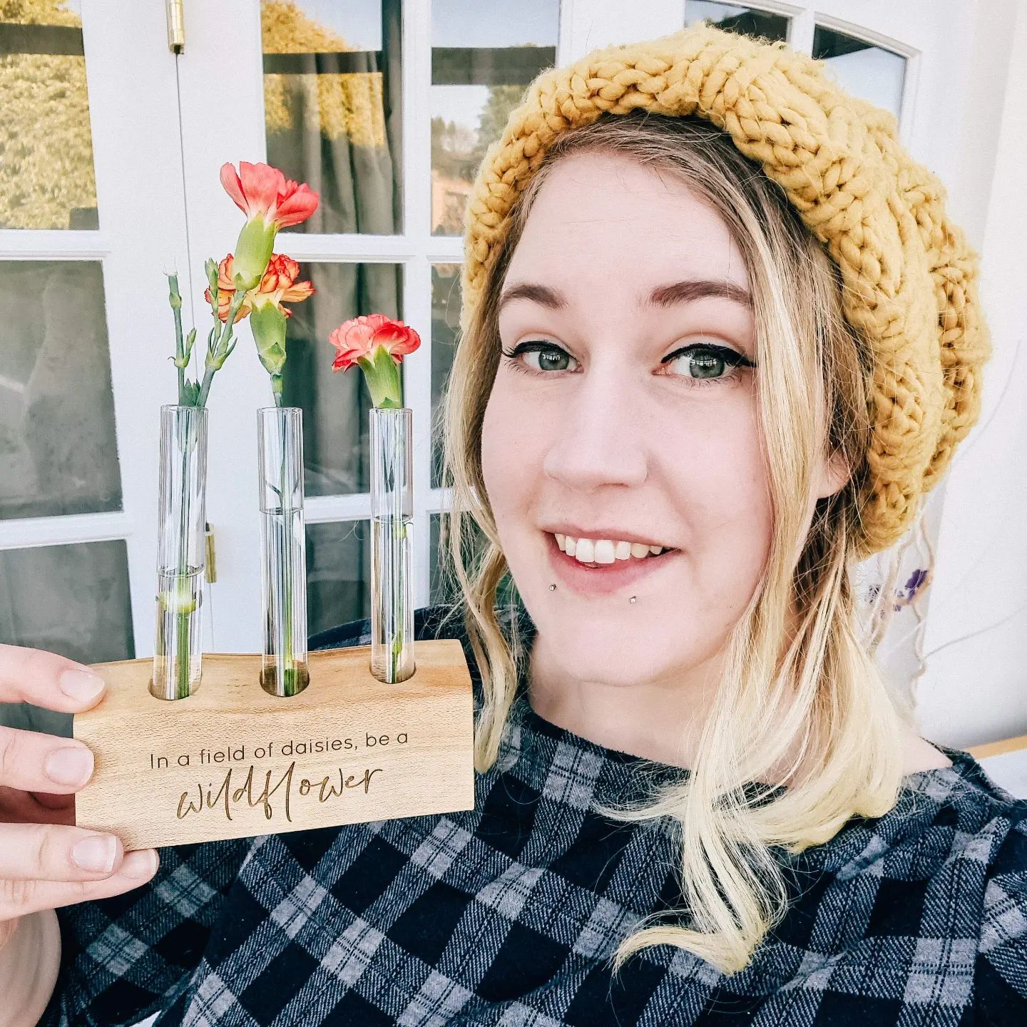 Lauren from Ingrained Inc holding a wildflower test tube vase that says in a field of daisies be a wildflower