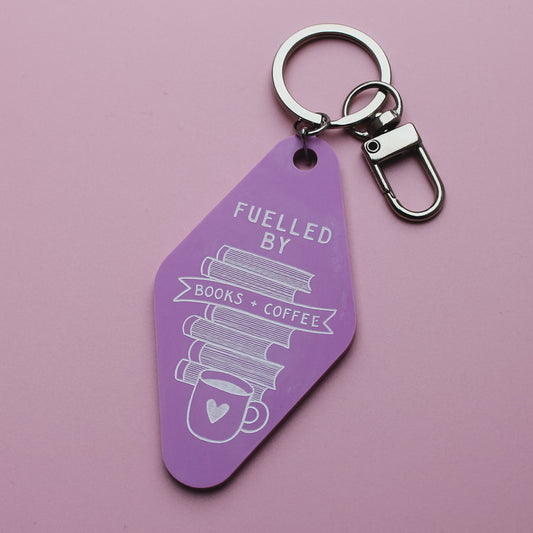 Pink motel style keychain with 'Fuelled by Books + coffee' text on a pink background