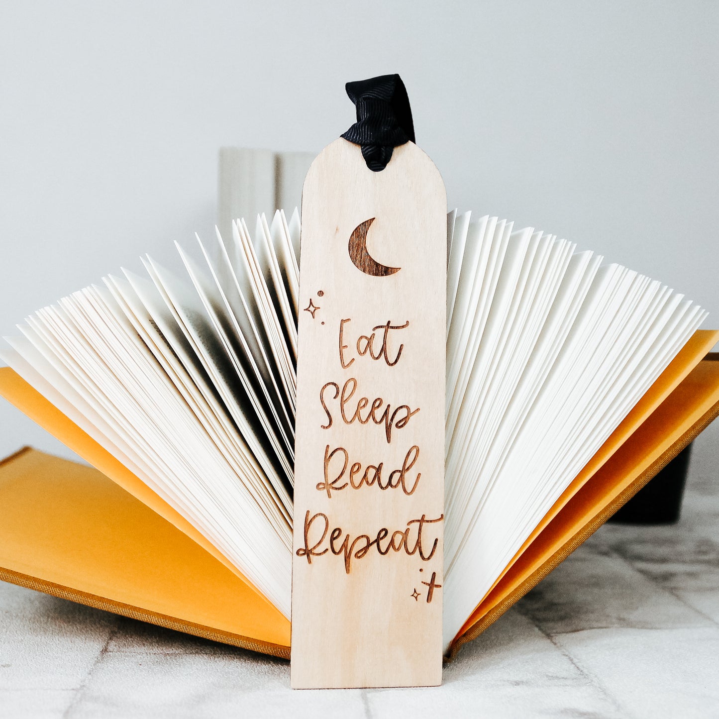 eat sleep read repeat wooden engraved bookmark for book lover. Engraved with a moon design and with a blue ribbon attached