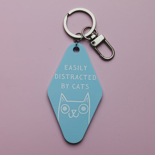 Blue motel style keyring with 'Easily Distracted by Cats' text and cat illustration on a pink background