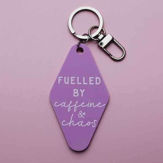 Pink motel style keychain with 'Fuelled by caffeine & chaos' text on a pink background