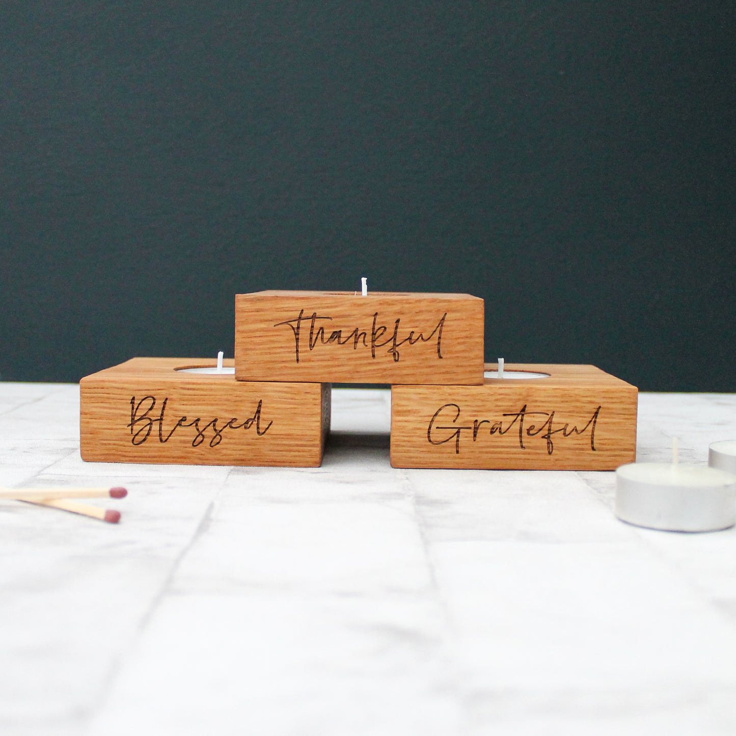 set of 3 solid oak tea light holders with the phrases grateful, thankful and blessed engraved on them