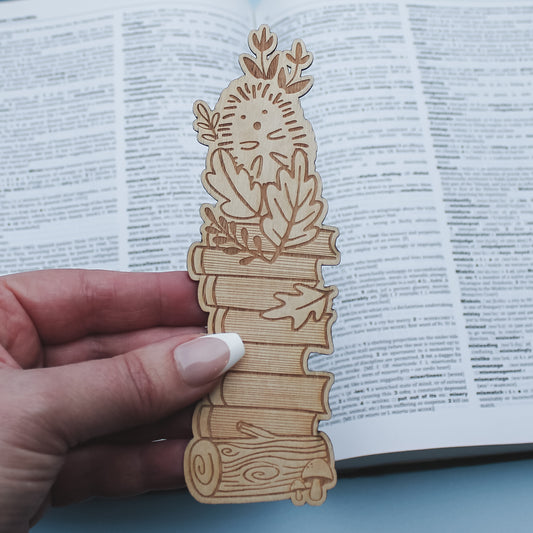 Wooden hedgehog woodland bookmark with decorative design held over an open book
