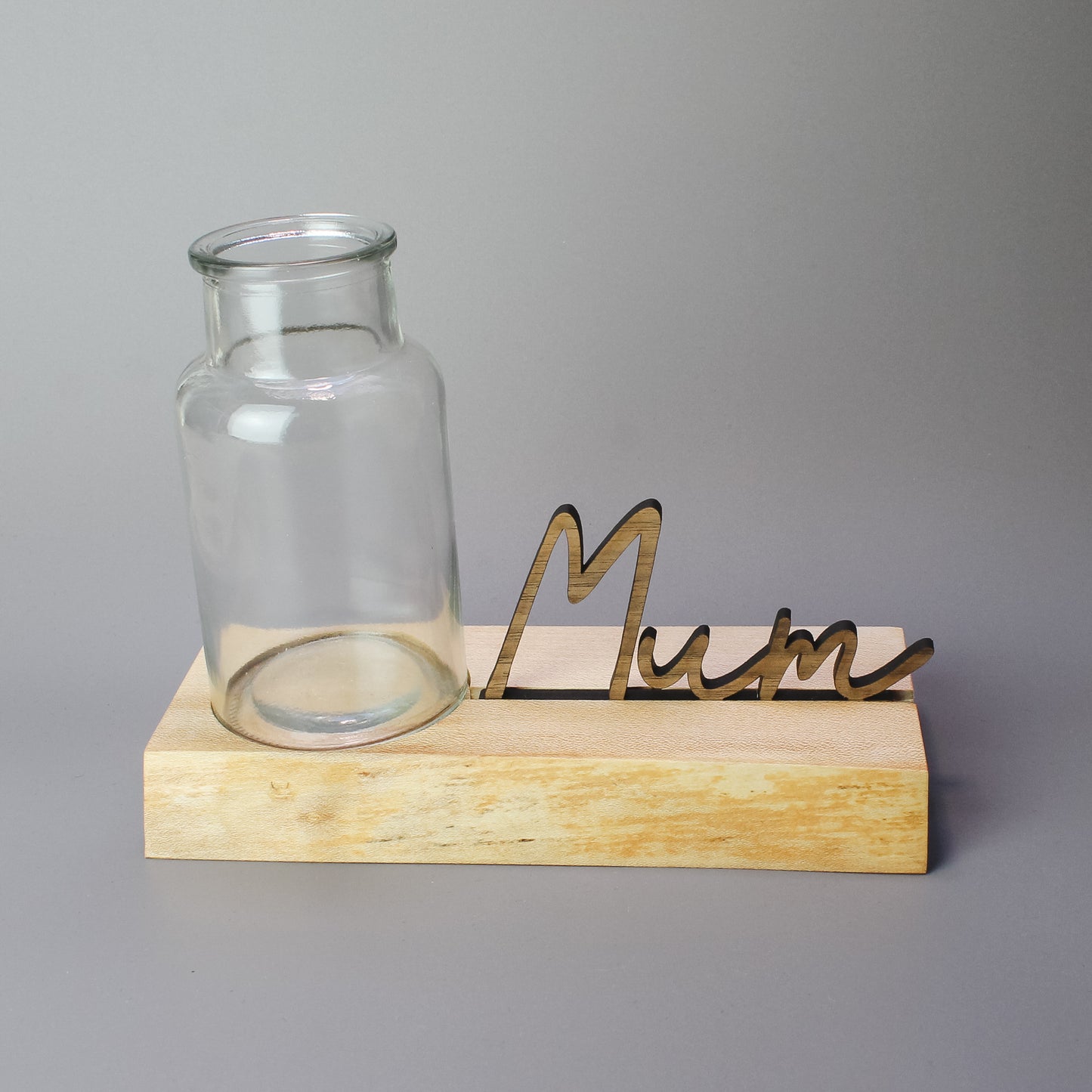 Close-up of a handmade wooden vase stand with a natural live edge and a carved recess to hold a glass vase – crafted from locally sourced elm wood