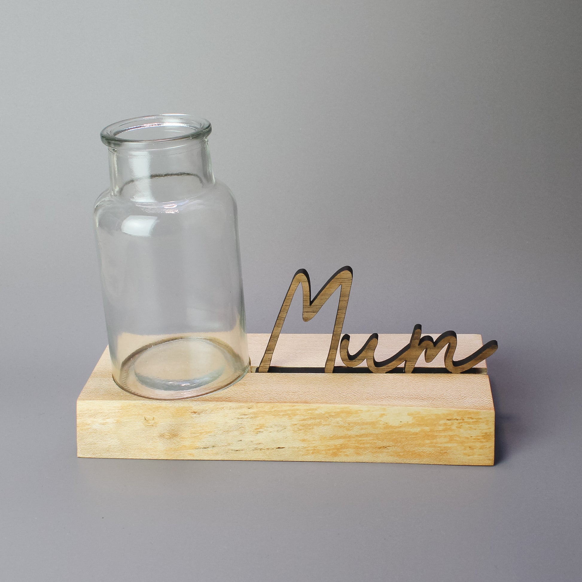 Close-up of a handmade wooden vase stand with a natural live edge and a carved recess to hold a glass vase – crafted from locally sourced elm wood