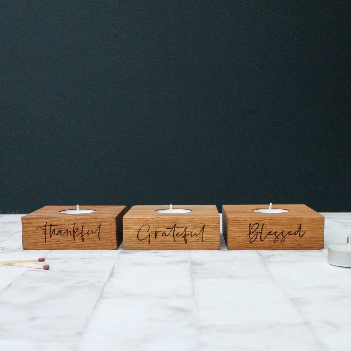set of 3 solid oak tea light holders with the phrases grateful, thankful and blessed engraved on them