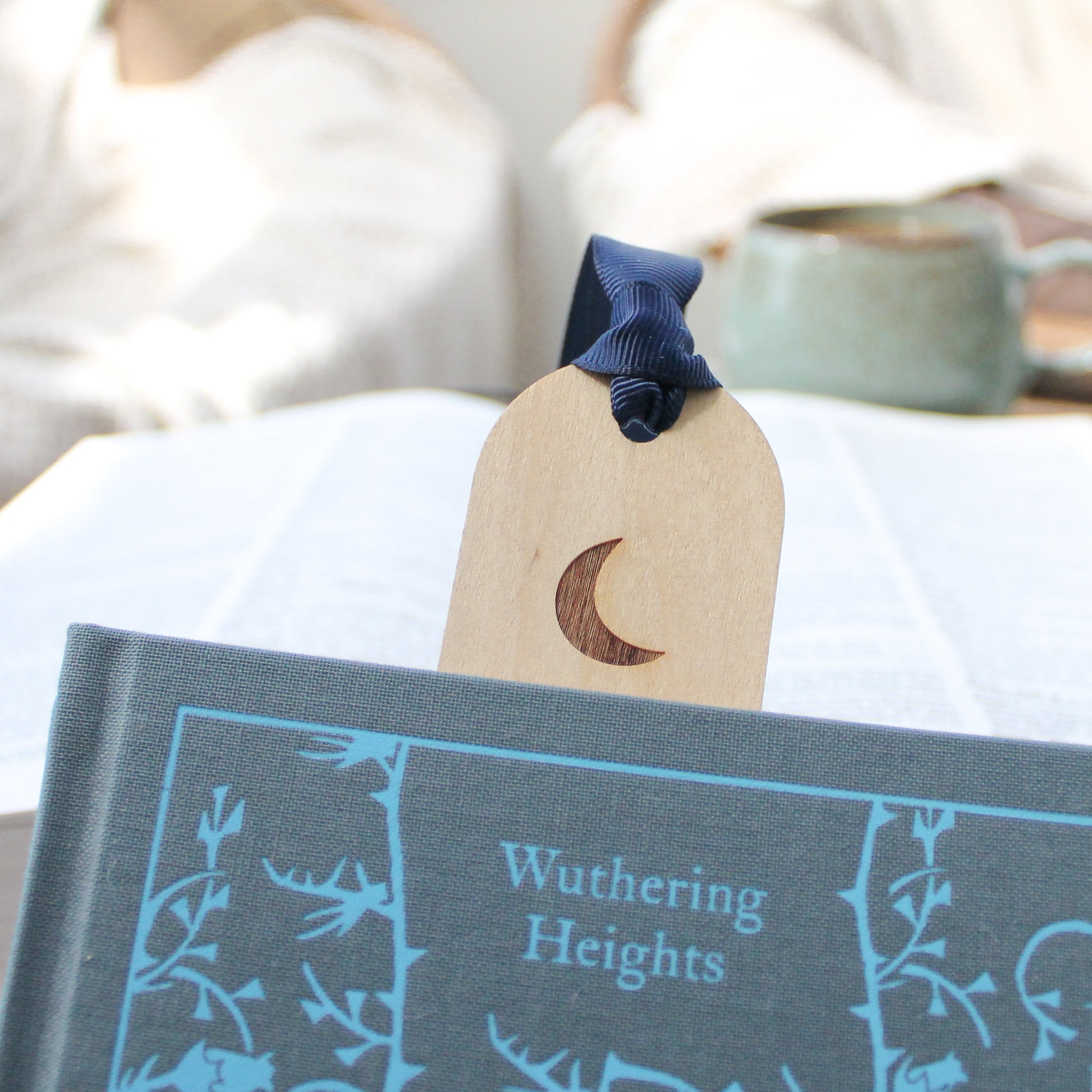 image of a wooden bookmark top sticking out of a book with crescent moon design