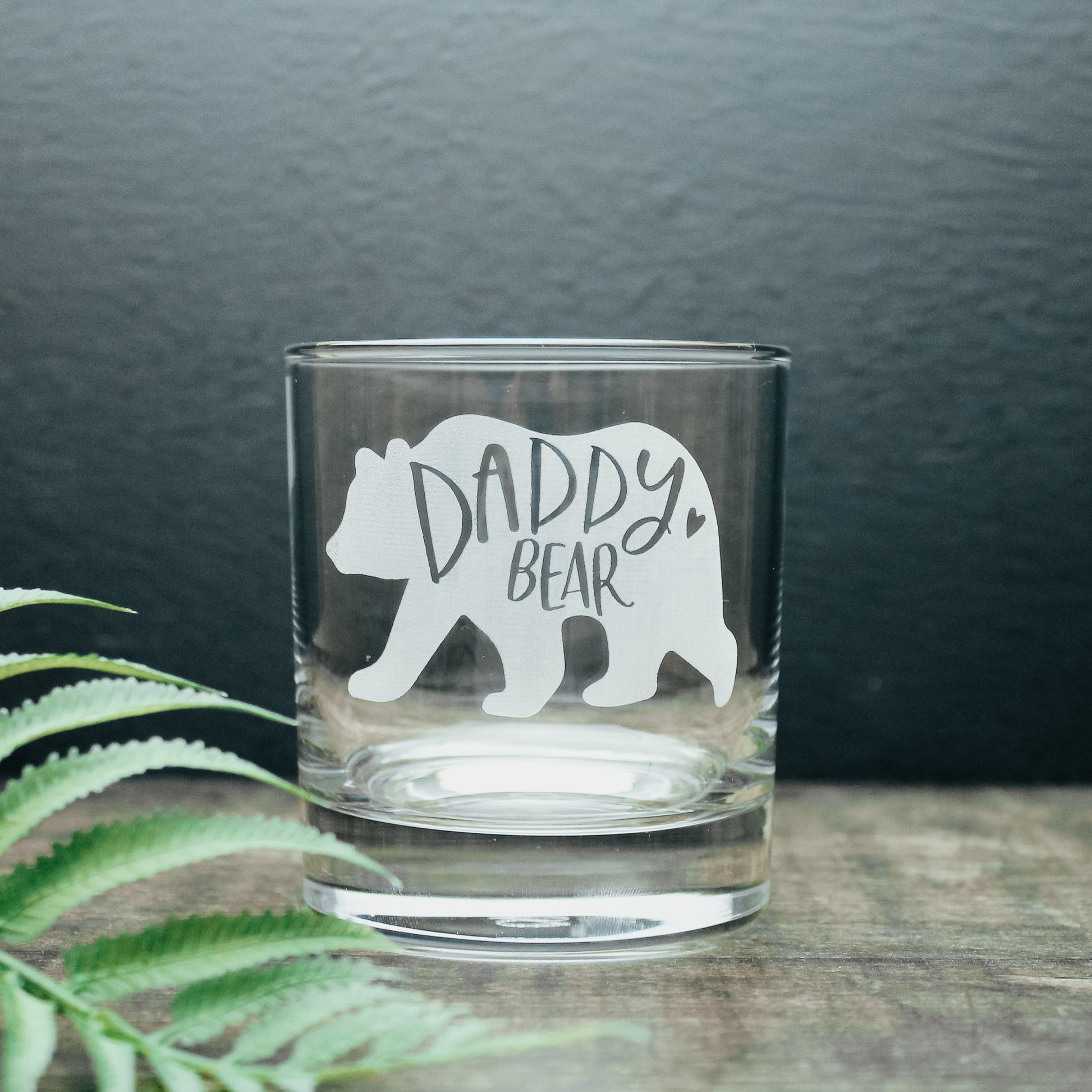 glass tumbler with the words daddy bear in a bear design engraved onto the glass in white