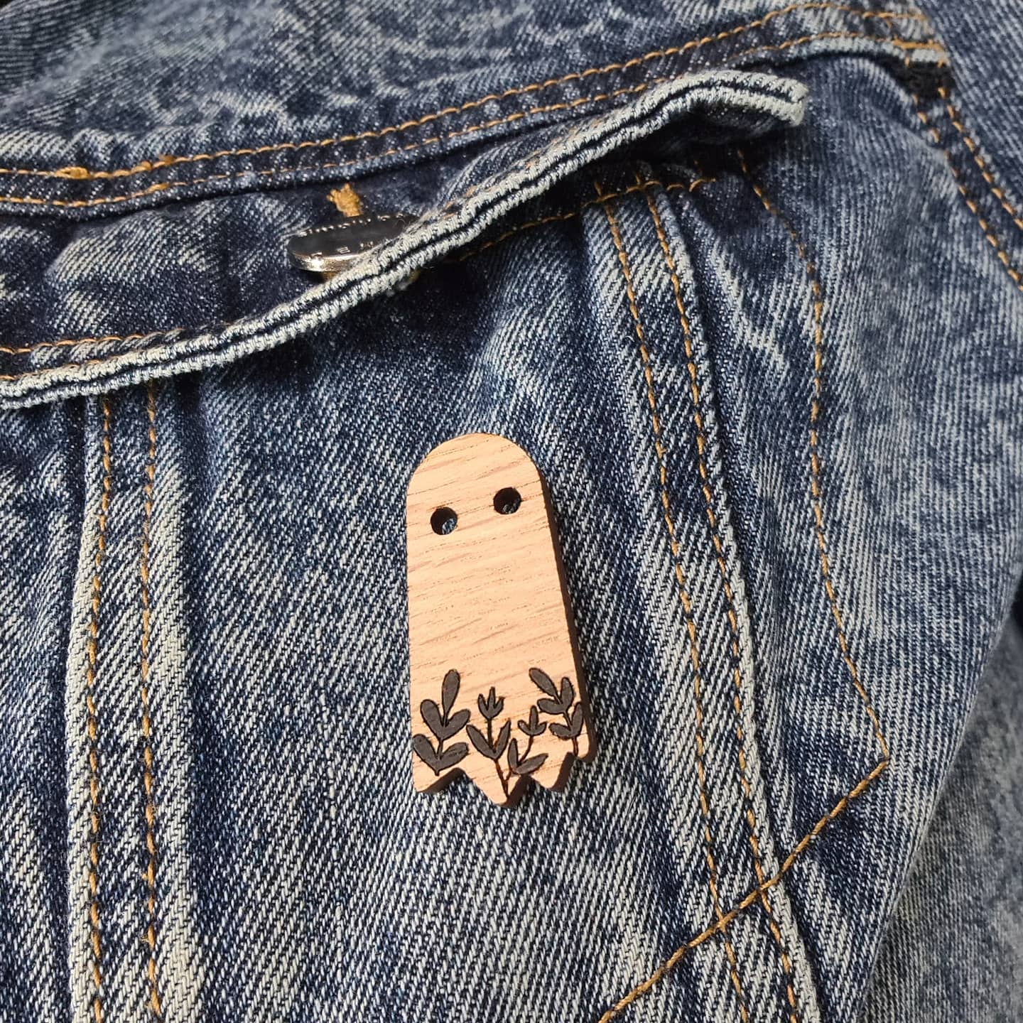 wooden ghost pin brooch affixed to a denim jacket