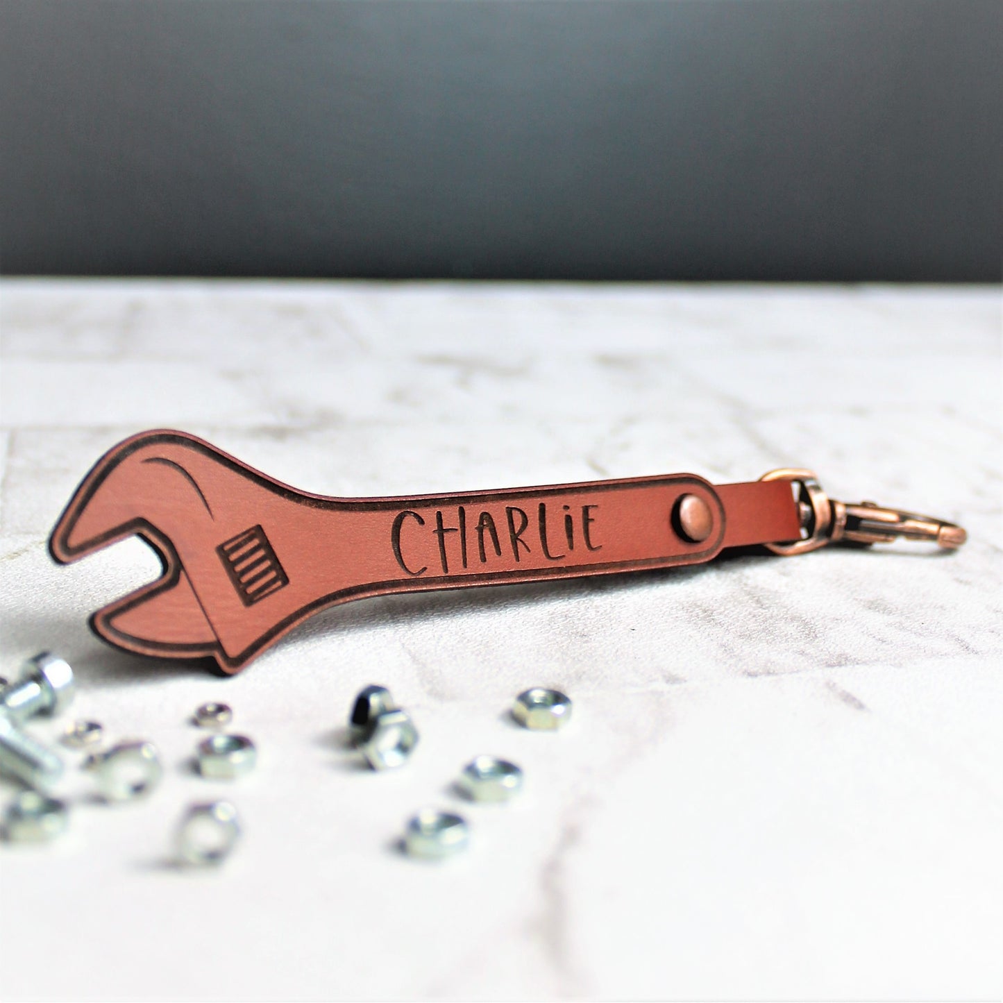 Leather personalised keyring with a name engraved onto it. Made from leather with a copper claps on