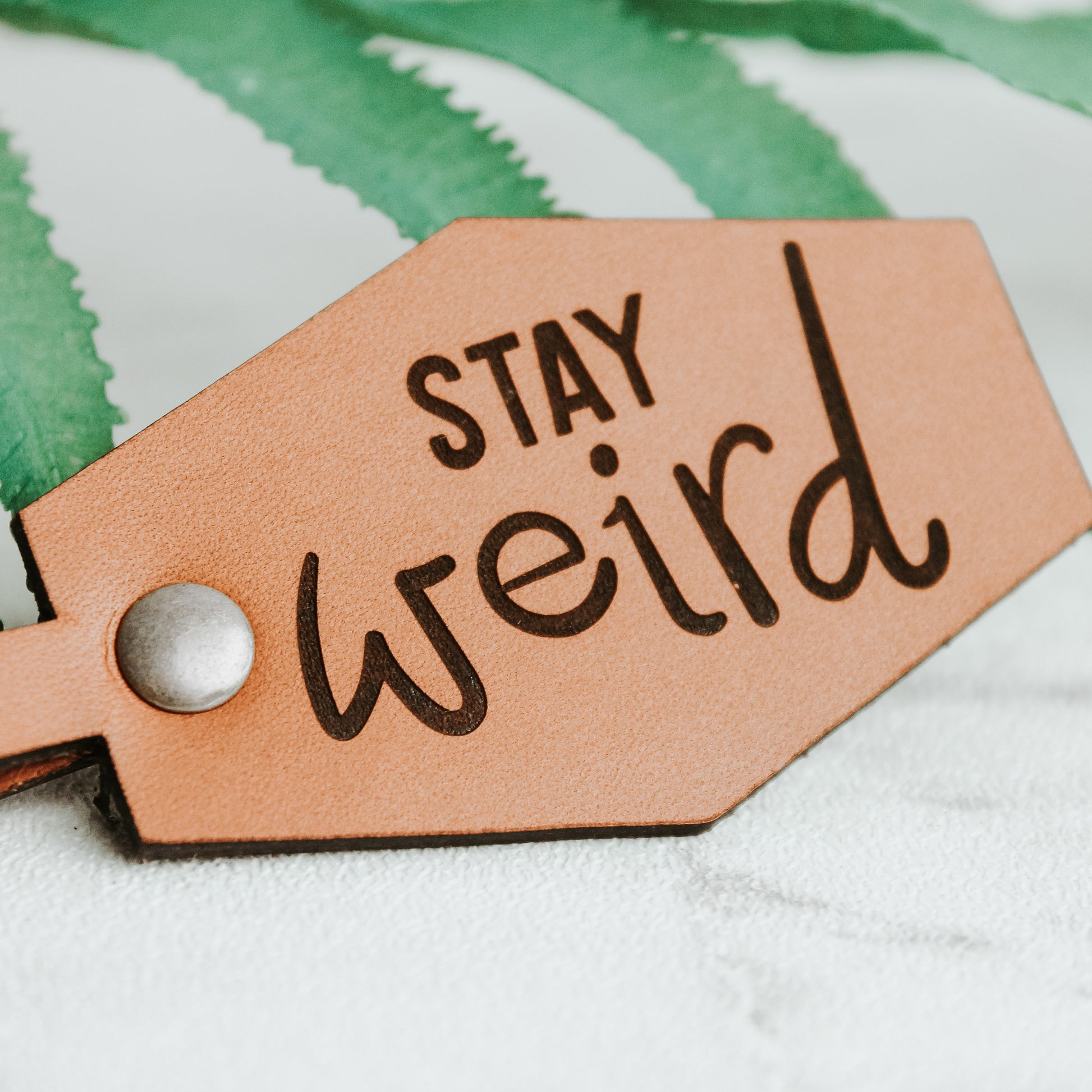 leather Keyring engraved with the words stay weird with real leather