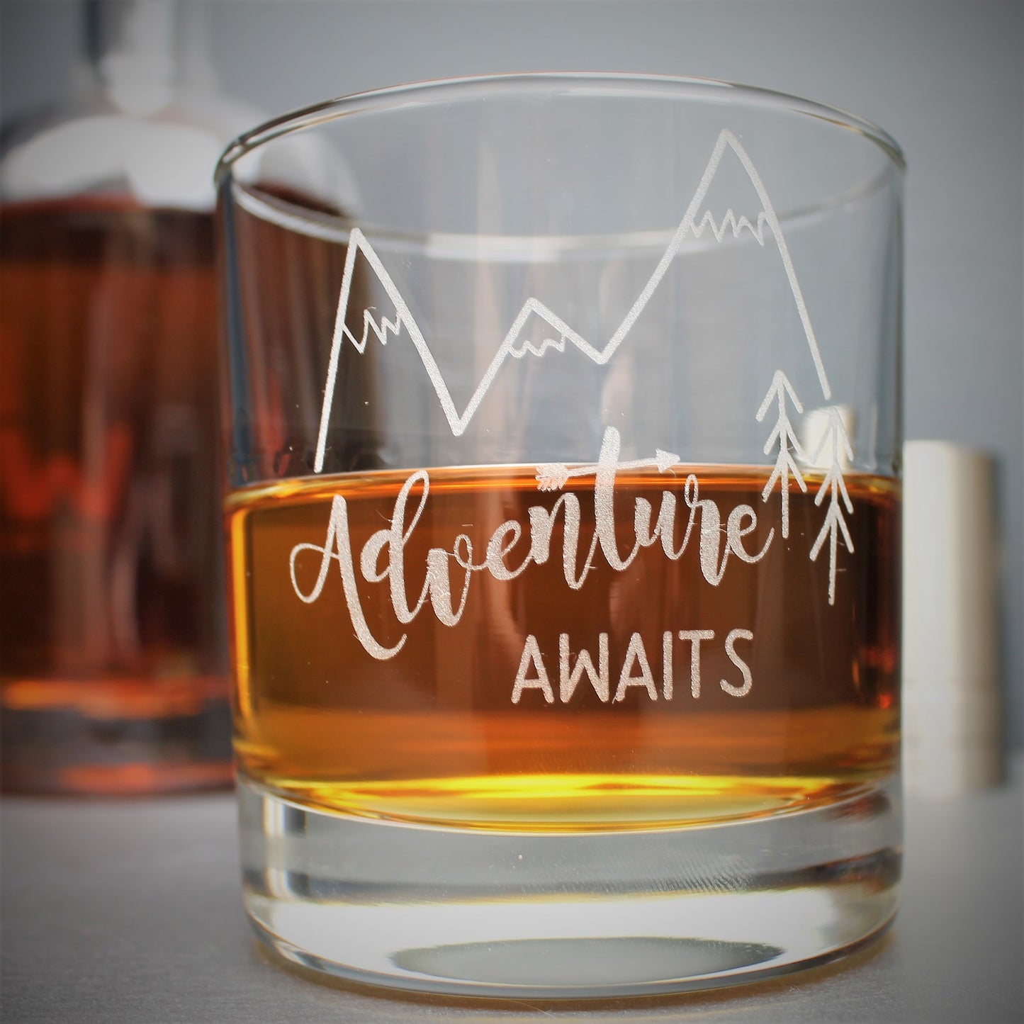 Engraved glass with mountain design and text that reads adventure awaits