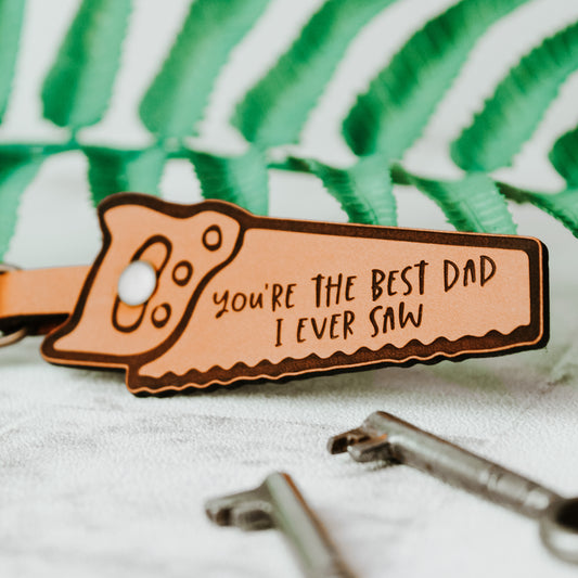 whisky colour keyring with the a funny saw pun for a joiner dad, up close image