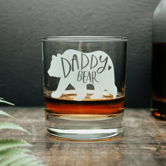 glass tumbler with white engraved bear with the words daddy bear engraved onto it with a short of whisky in the glass
