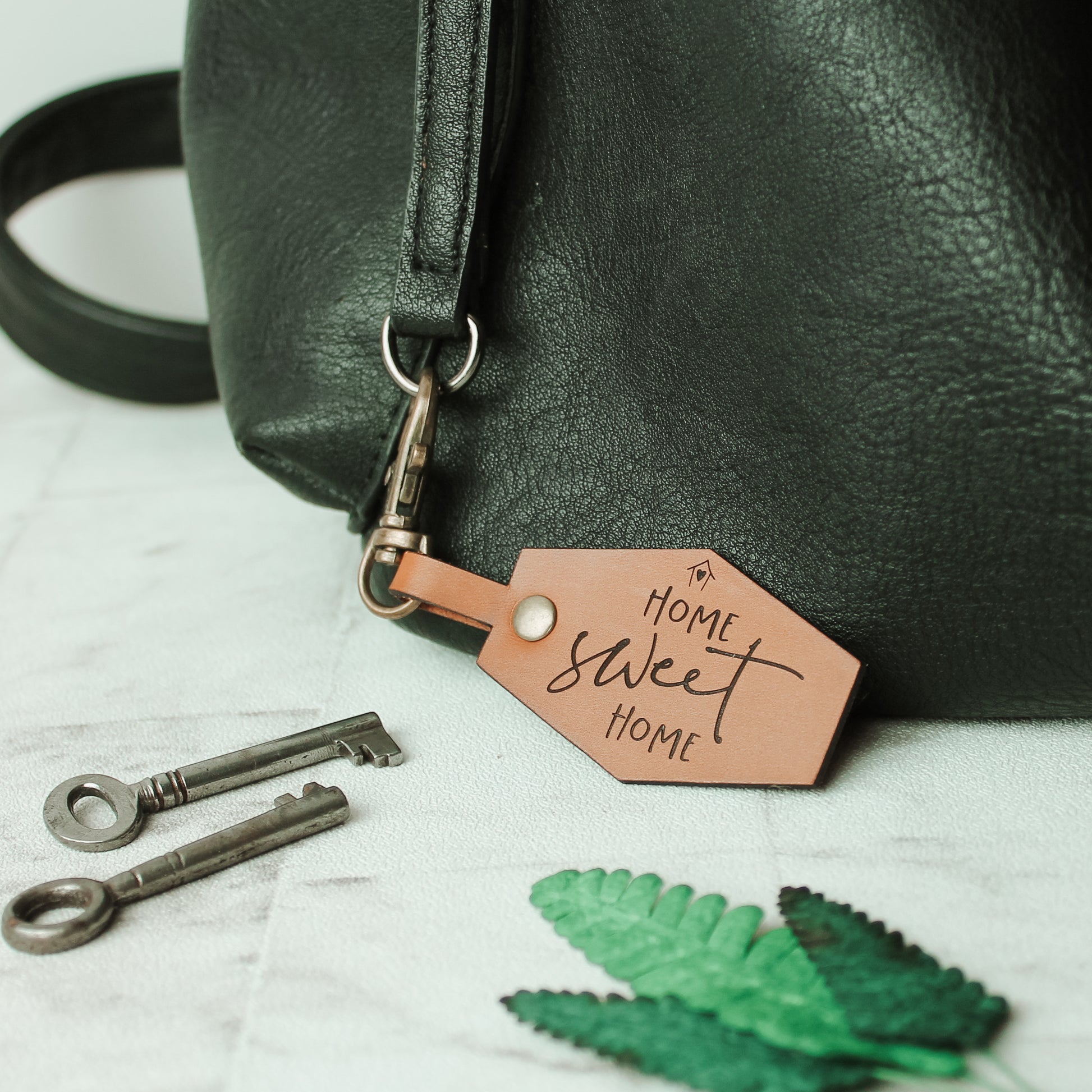 leather bag tag engraved with the wording home sweet home with a swivel keyring clasp
