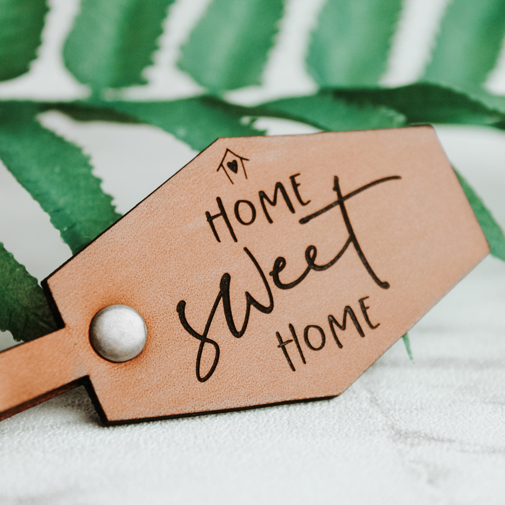 leather keyring showing an up close image of the text home sweet home on a whisky coloured leather