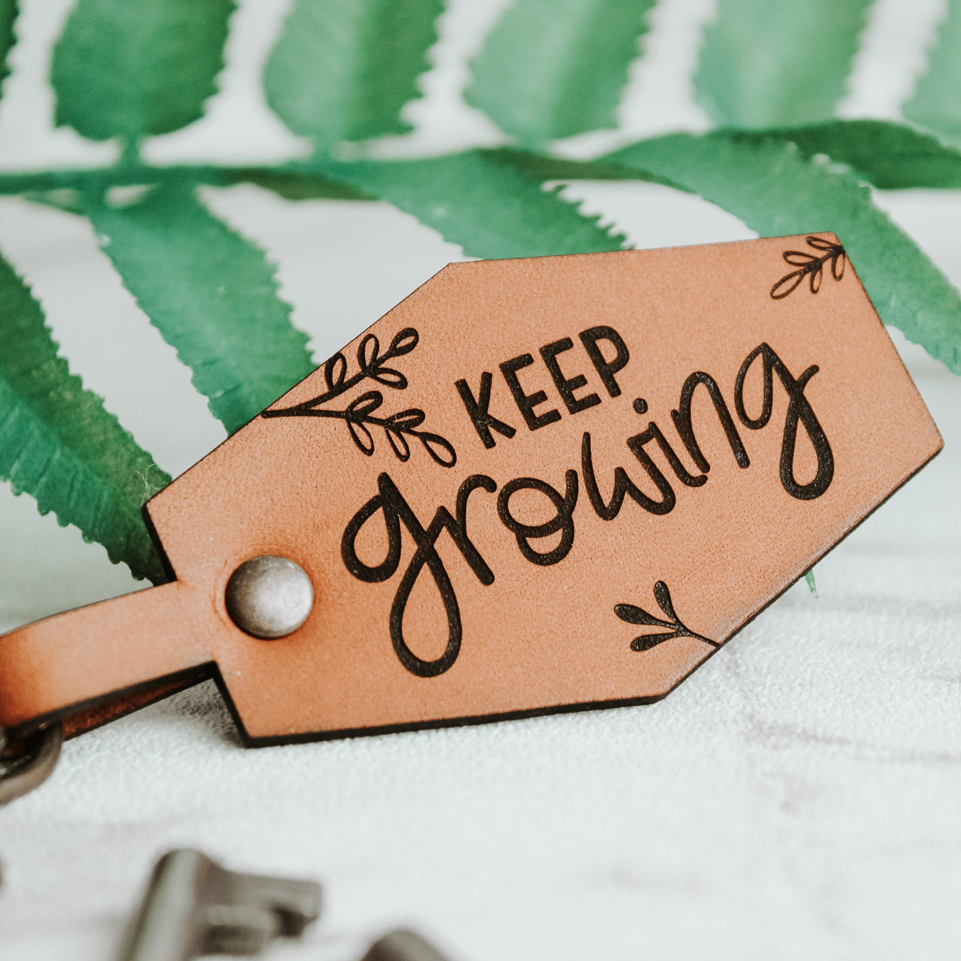 positive affirmation keyring with engraved words keep growing made from whisky coloured leather