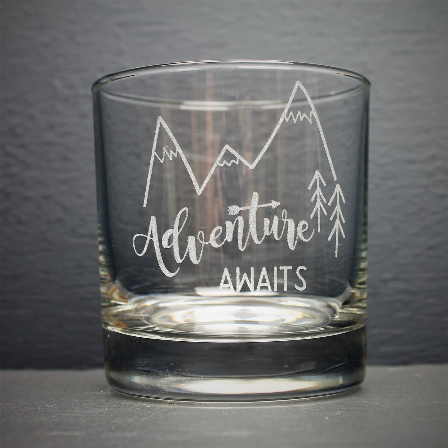 Engraved glass with mountain design and text that reads adventure awaits