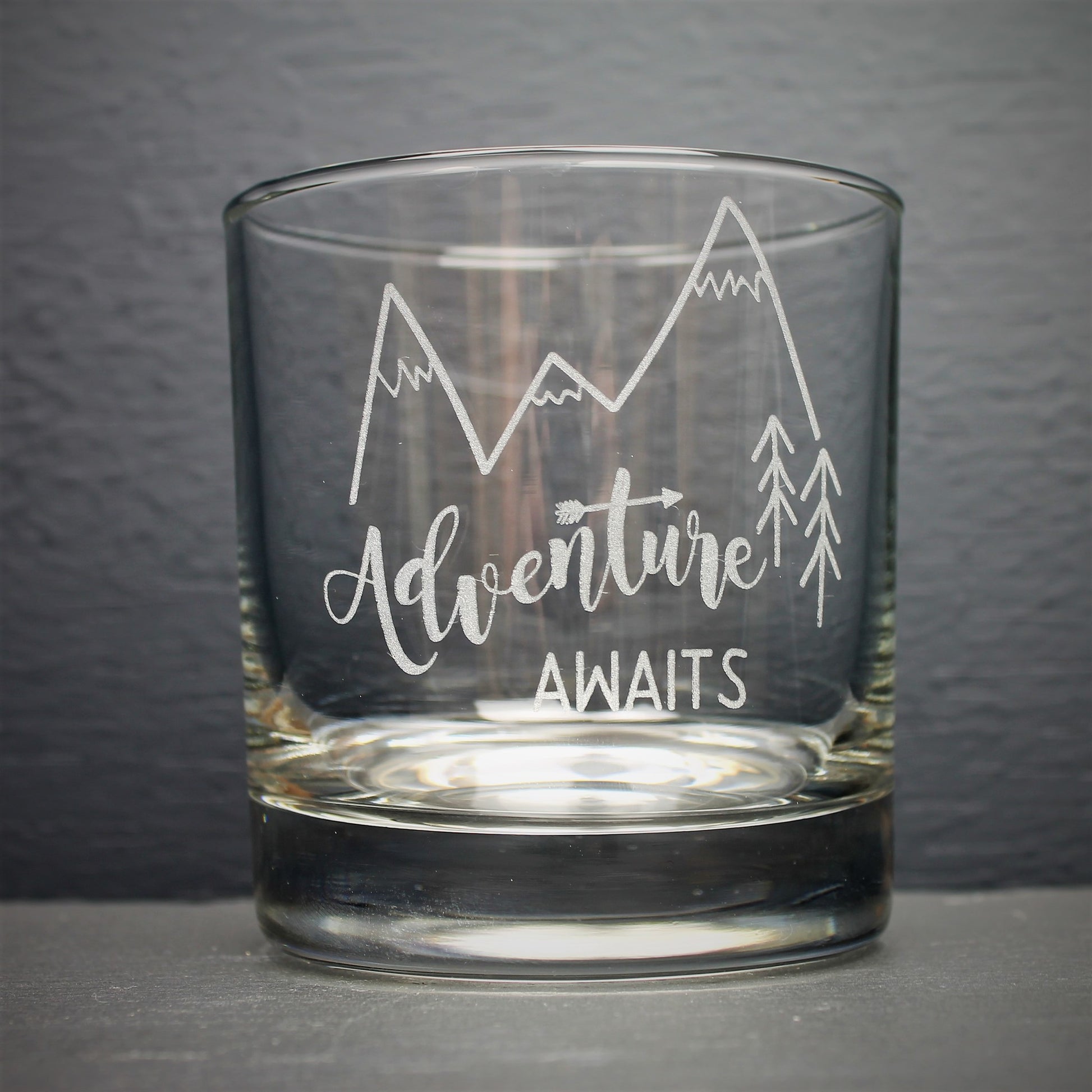 Engraved glass with mountain design and text that reads adventure awaits