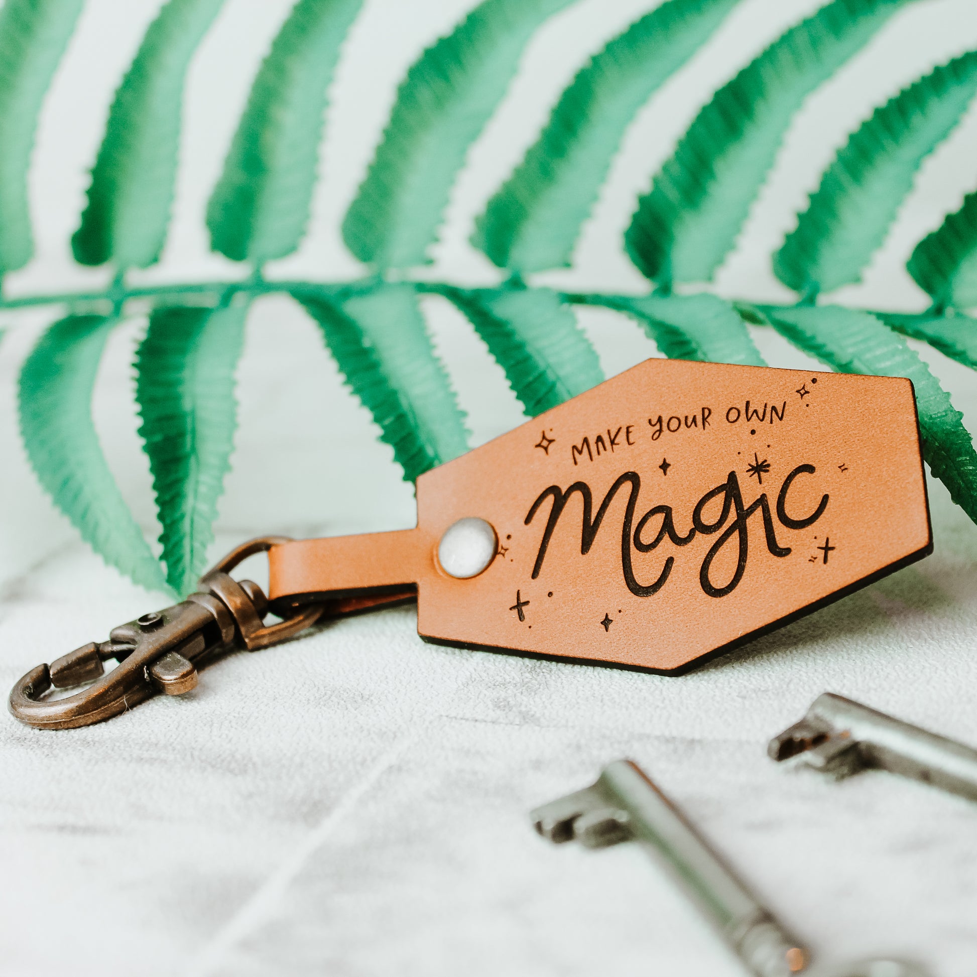 whisky coloured leather keyring engraved with the words: make your own magic. With celestial design around