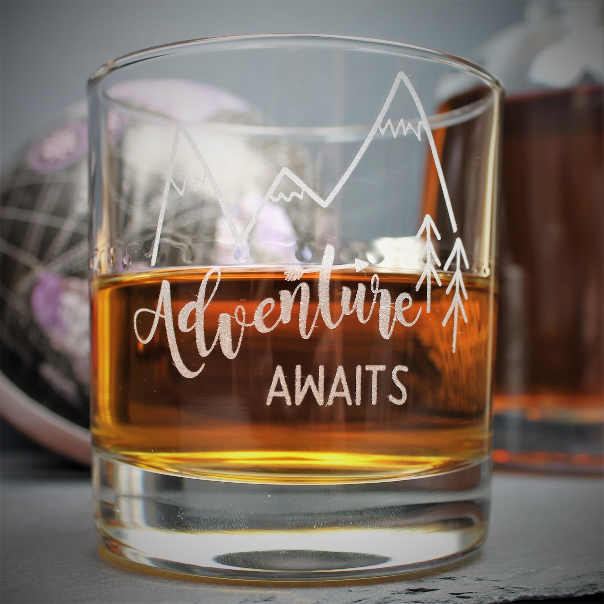 Engraved glass with mountain design and text that reads adventure awaits