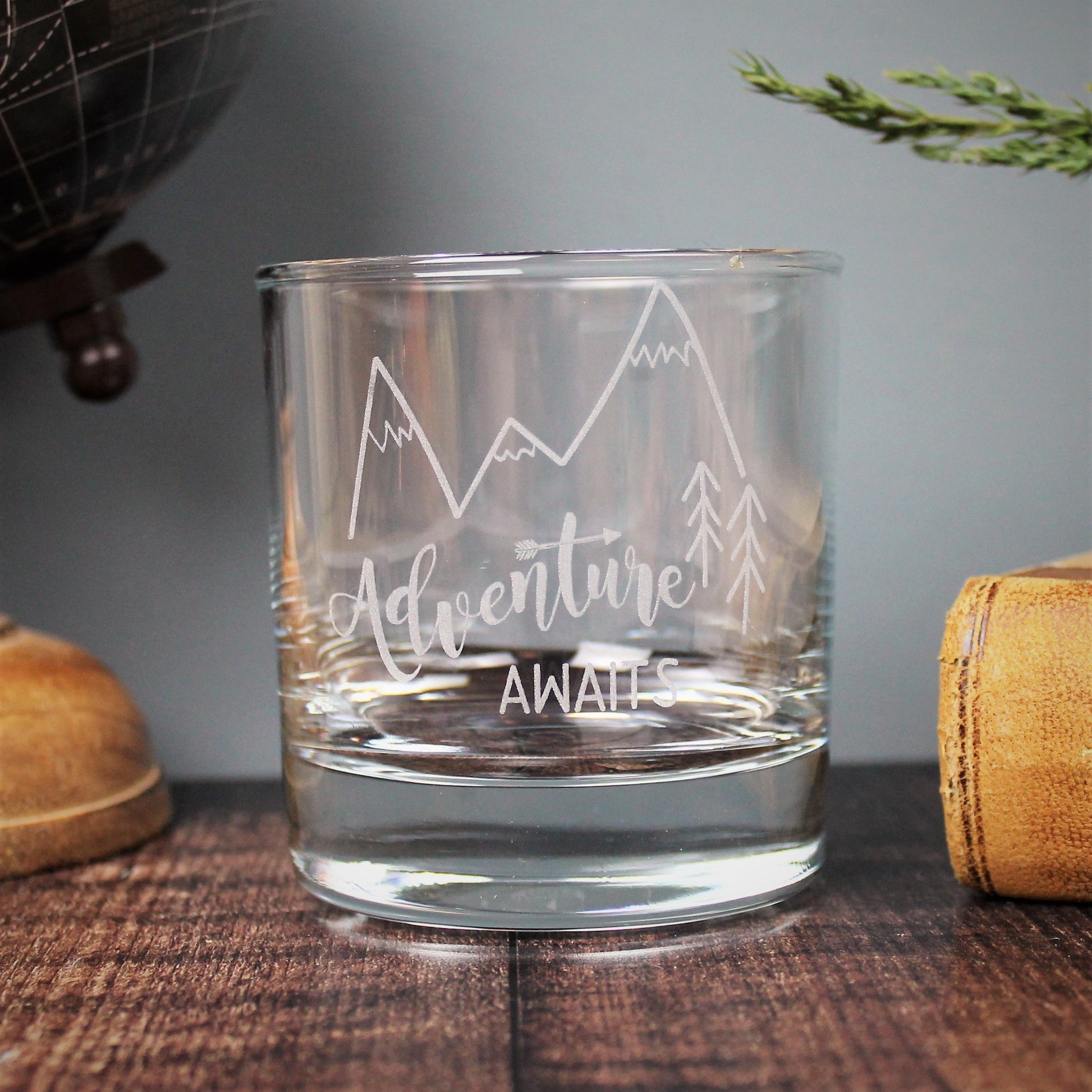 Engraved glass with mountain design and text that reads adventure awaits