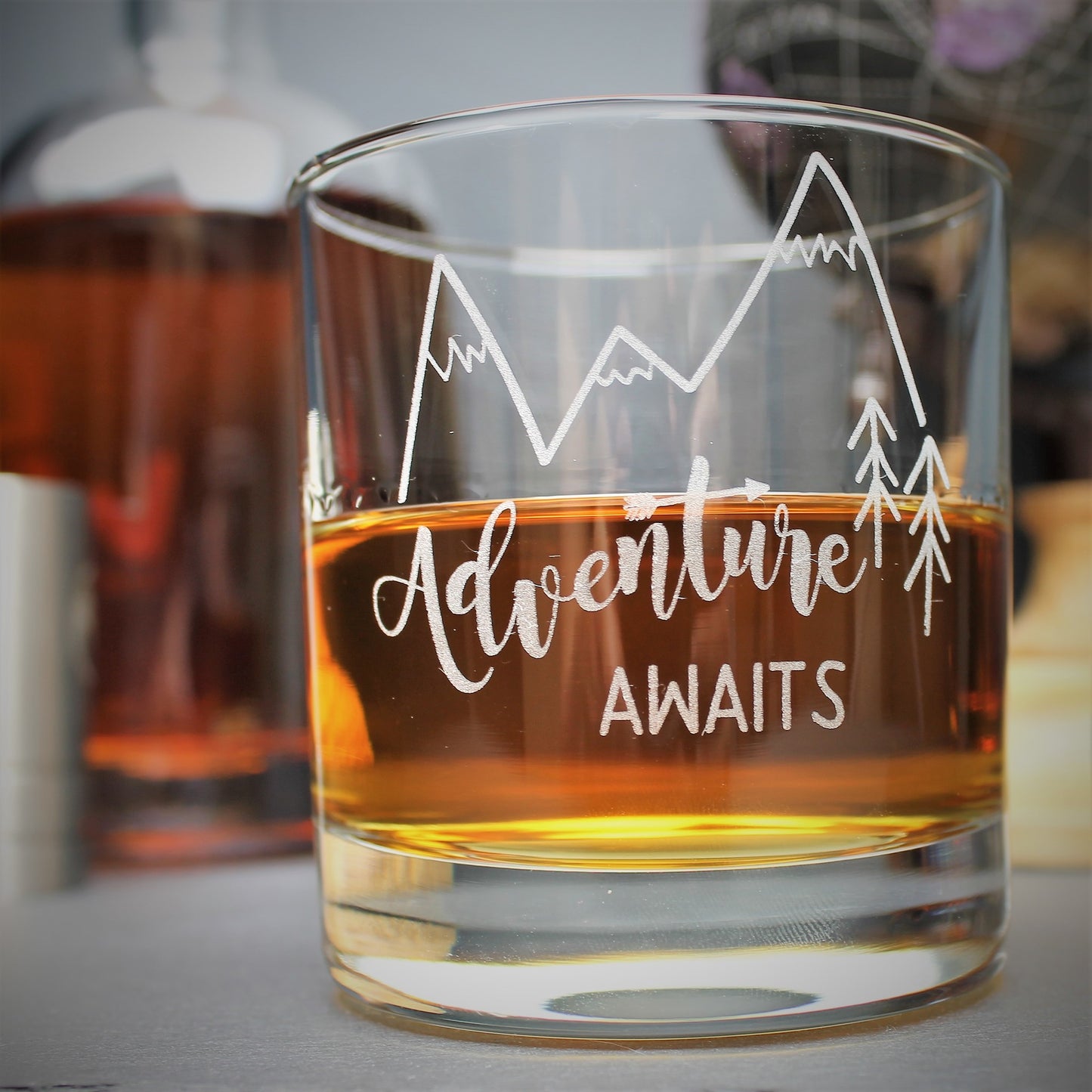 Engraved glass with mountain design and text that reads adventure awaits