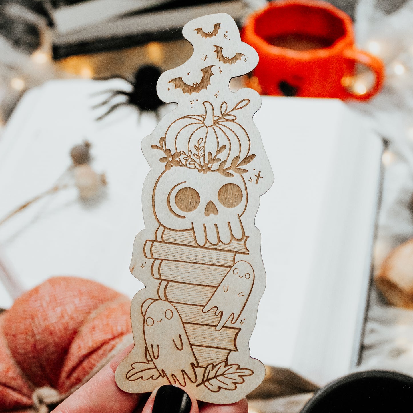 Spooky Cute Halloween bookmark made from wood, engraved with a haunted bookstack featuring a skull, pumpkin, ghosts and bat design 