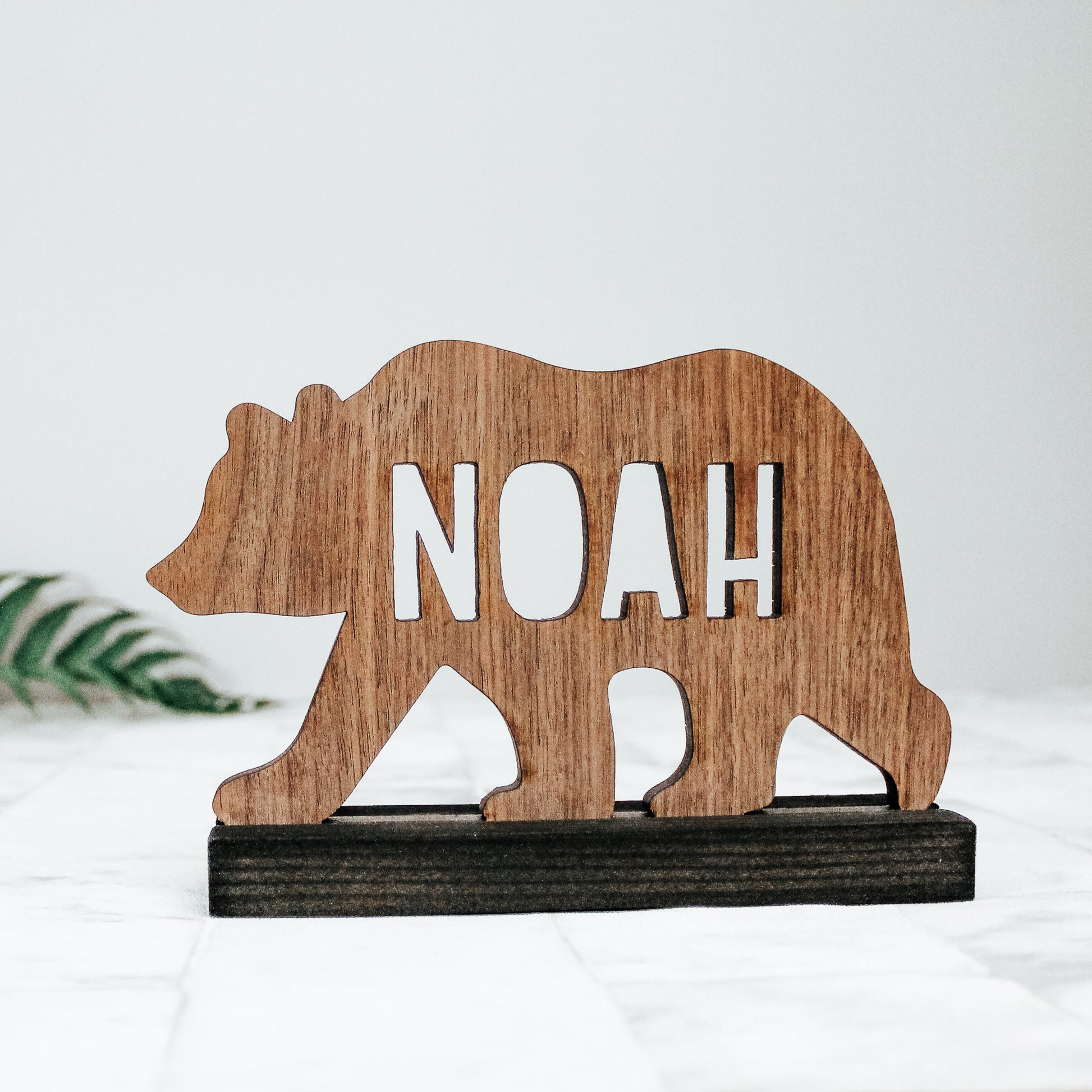 wooden bear silhouette with laser cut name and black plinth that it sits on. Perfect for a woodland theme nursery