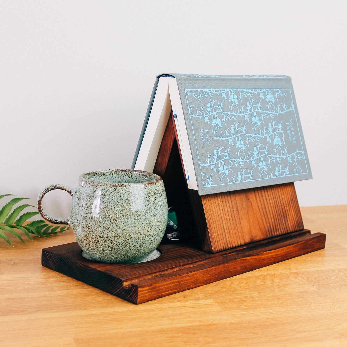 The perfect companion for your next reading session: a dark wooden book valet and a steaming cup of tea.