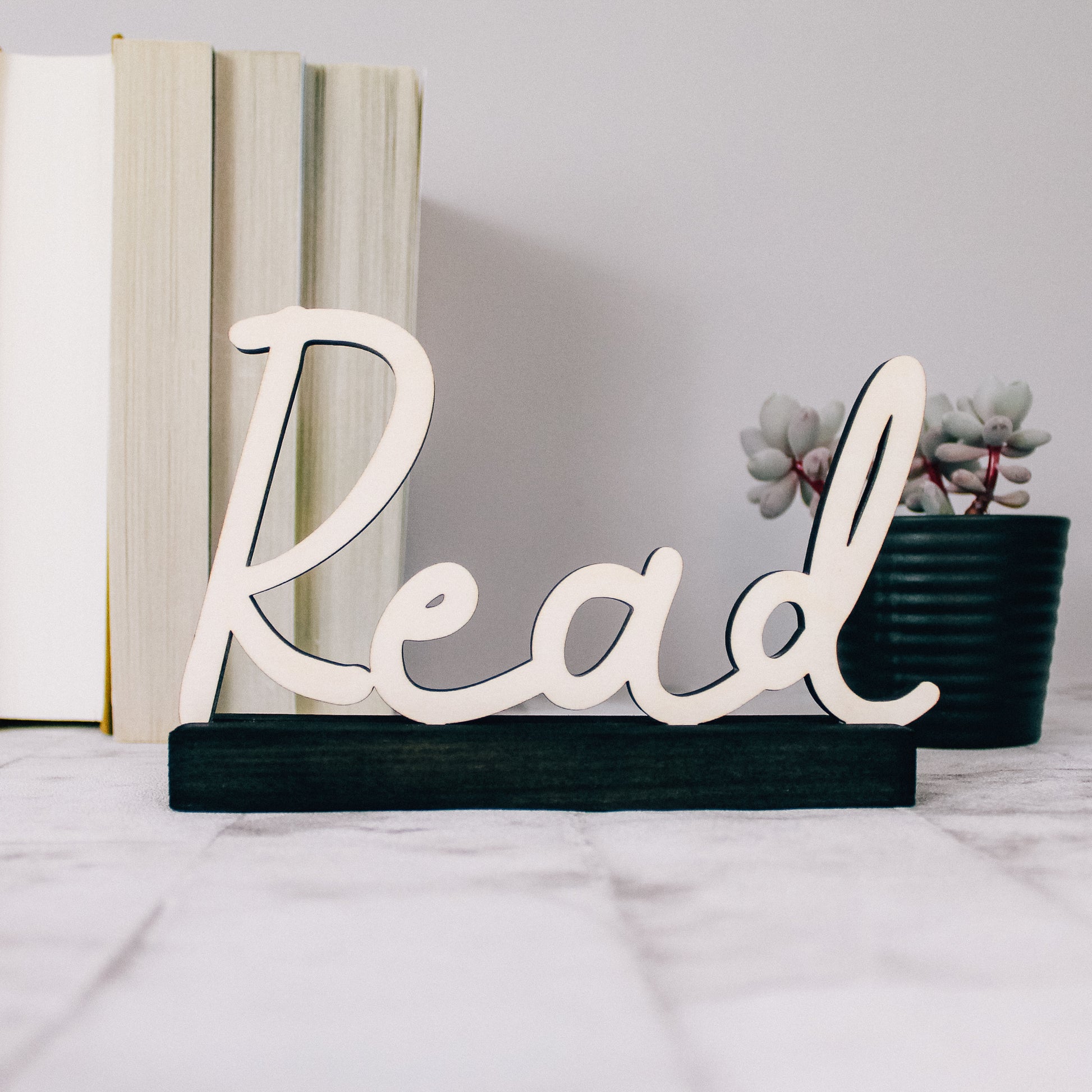 bookshelf decor wooden read sign with natural wood coloured writing and a black coloured base