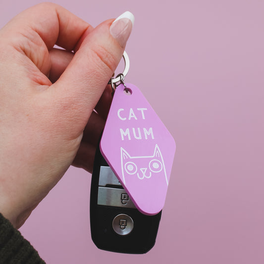 Motel Style Keychain with 'Cat Mum' tag held by a hand against a pink background