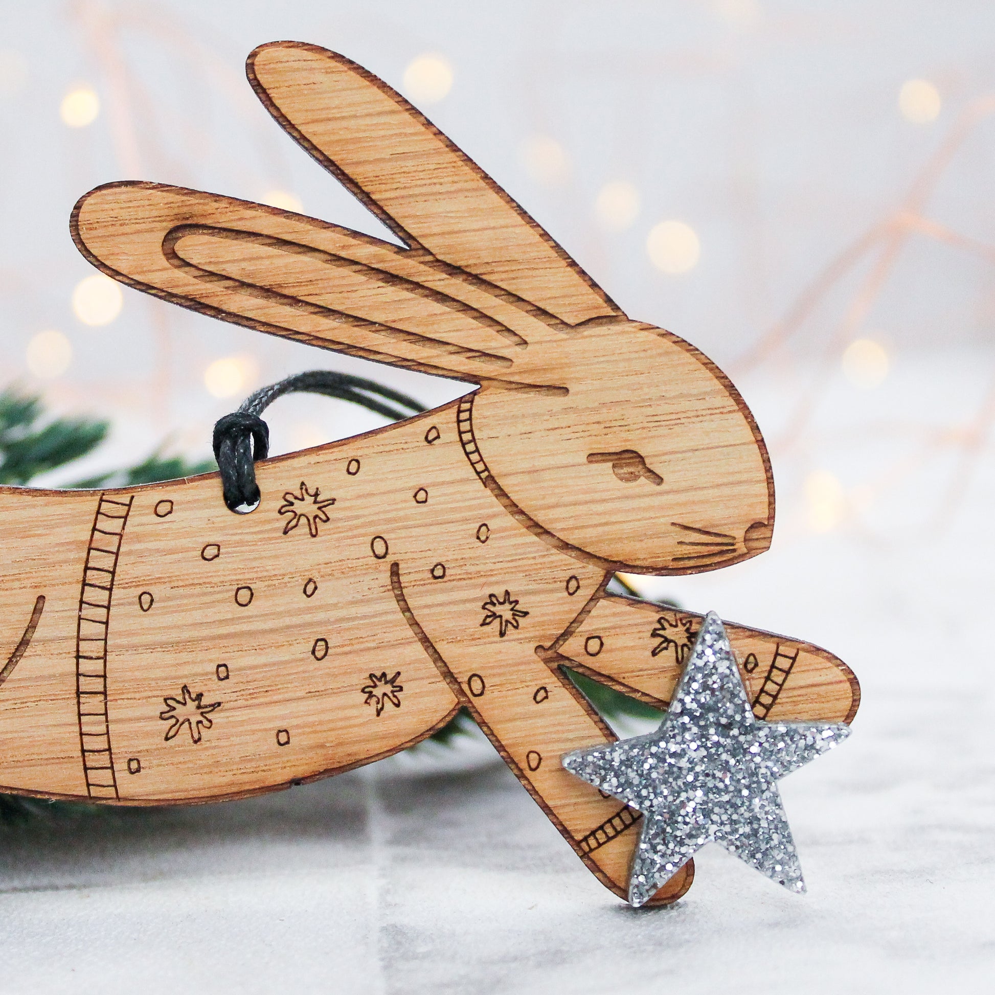 wooden rabbit Christmas tree decoration in winter jumper and holding a silver star