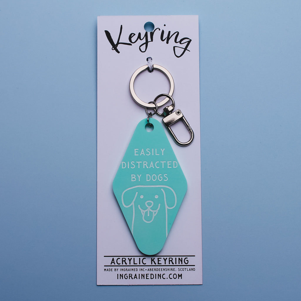 Mint coloured acrylic motel style keychain with 'Easily Distracted by Dogs' text on, attached to white packaging 