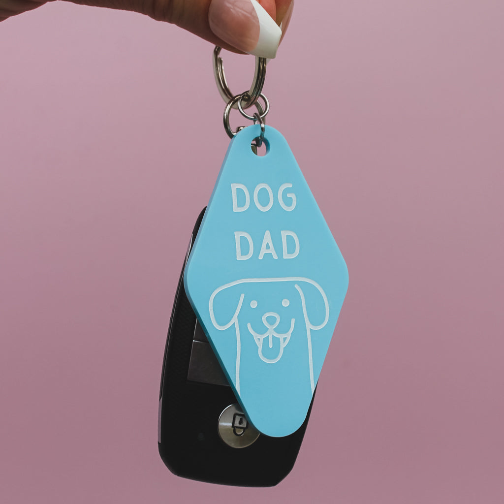 Motel Style Keychain with 'DOG DAD' text and dog illustration on a pink background