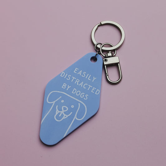 Blue motel style keychain with 'Easily Distracted by Dogs' text on a pink background