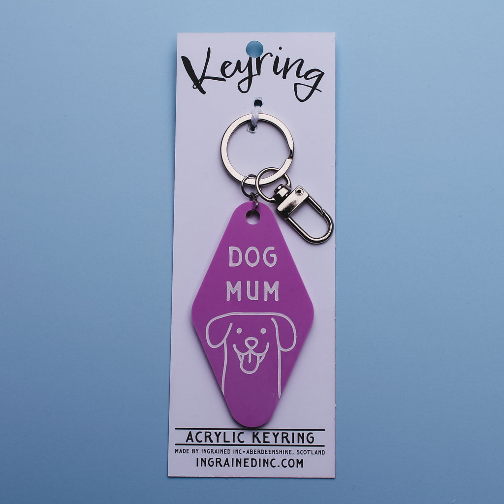 Pink acrylic Motel Style keyring with 'DOG MUM' text on a white card against a blue background