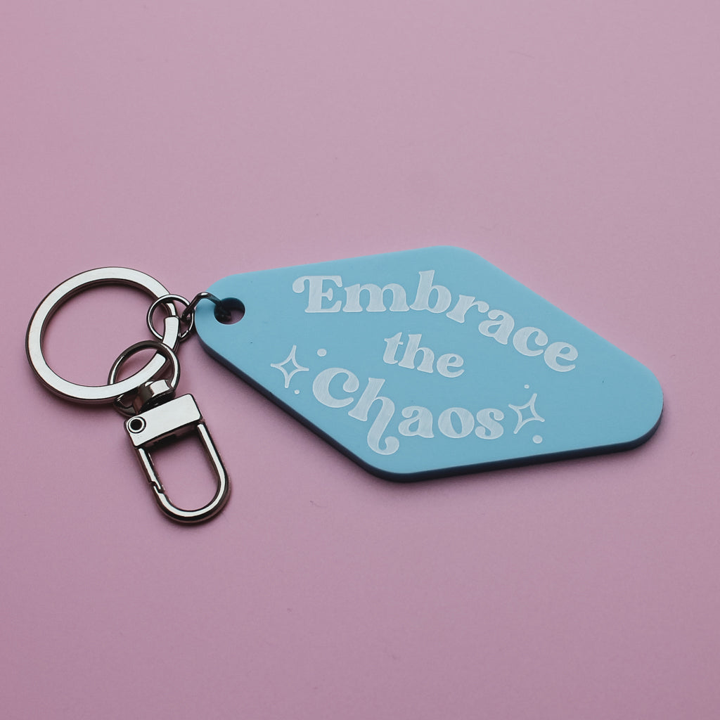 Motel style Keychain with a blue tag that says 'Embrace the chaos' on a pink background