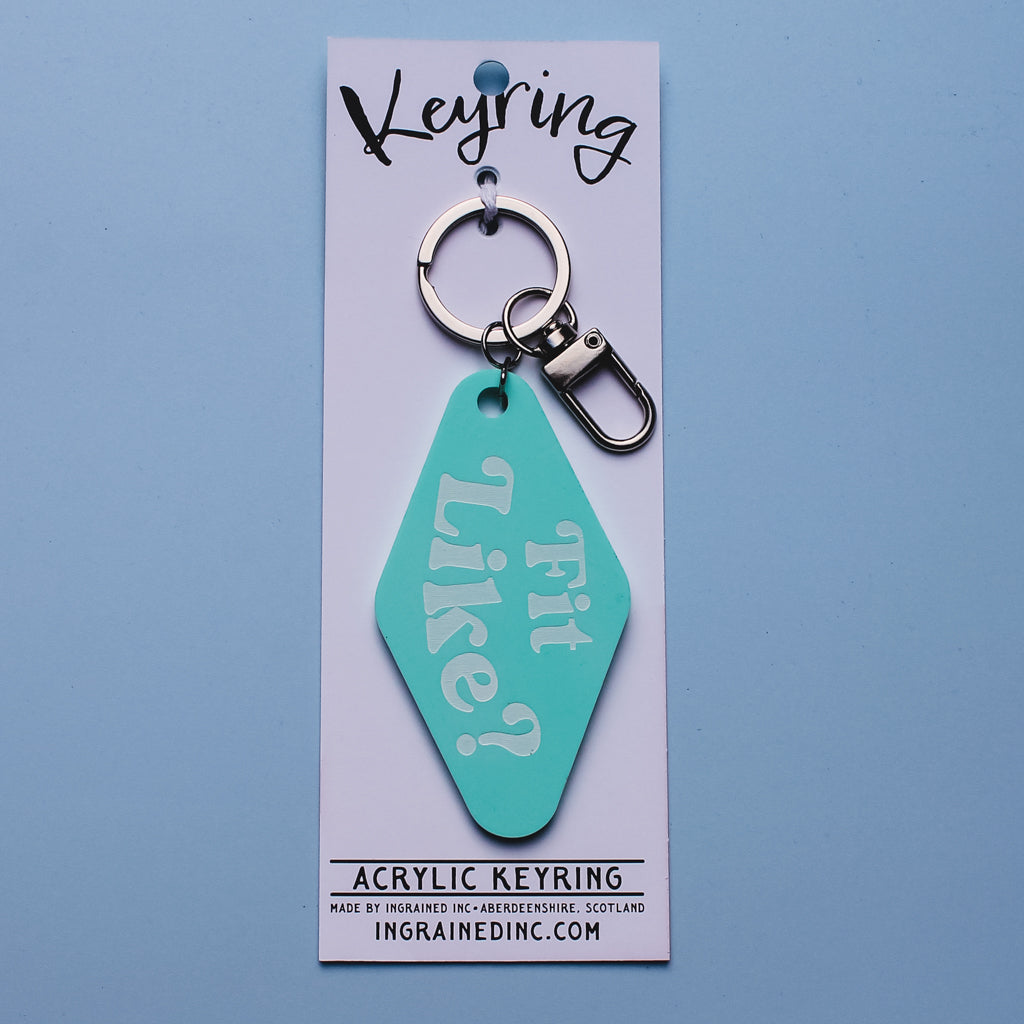 Teal motel style acrylic keyring on a white backing card with 'fit like?' engraved on it against a light blue background