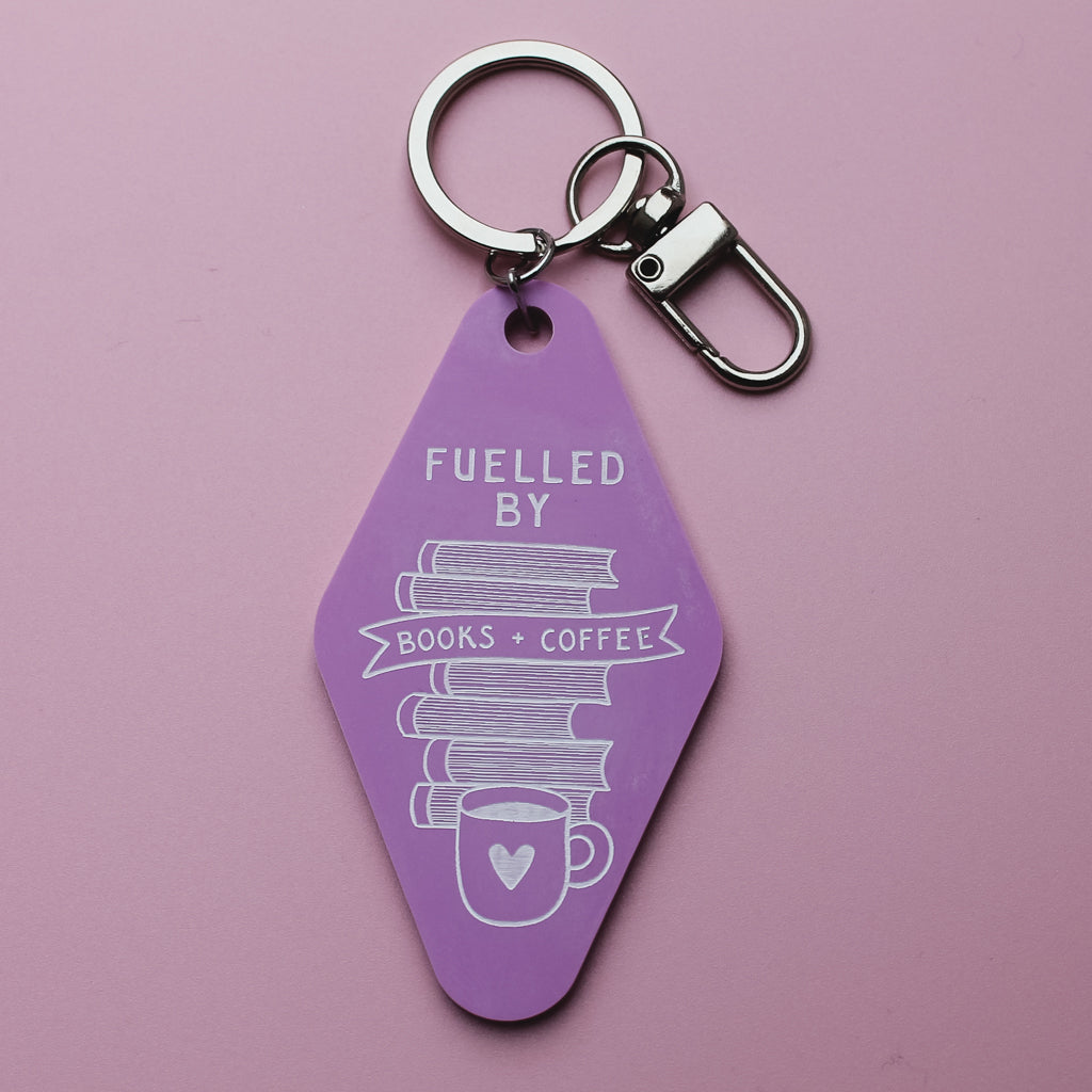 Pink motel style keychain with 'Fuelled by Books + coffee' text on a pink background