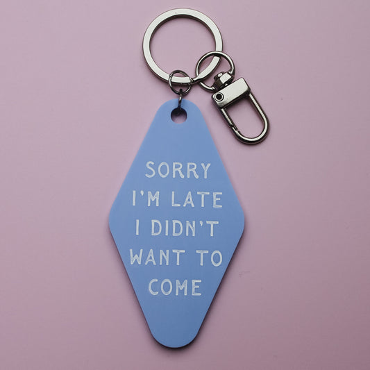 Blue Motel style keyring tag with white text saying 'sorry i'm late I didn't want to come' on a pink background