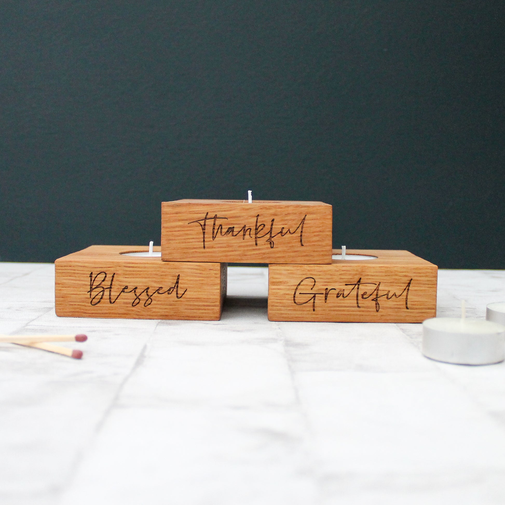 set of 3 solid oak tea light holders with the phrases grateful, thankful and blessed engraved on them 