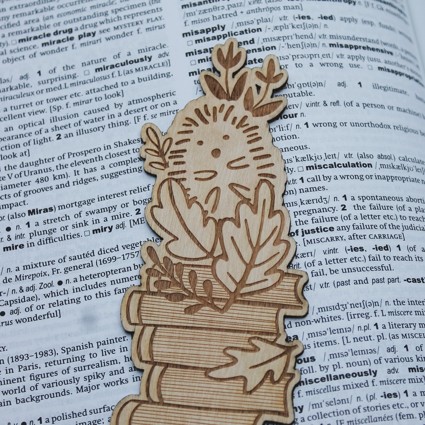 Wooden bookmark shaped like a hedgehog and autumnal leaves on an open book
