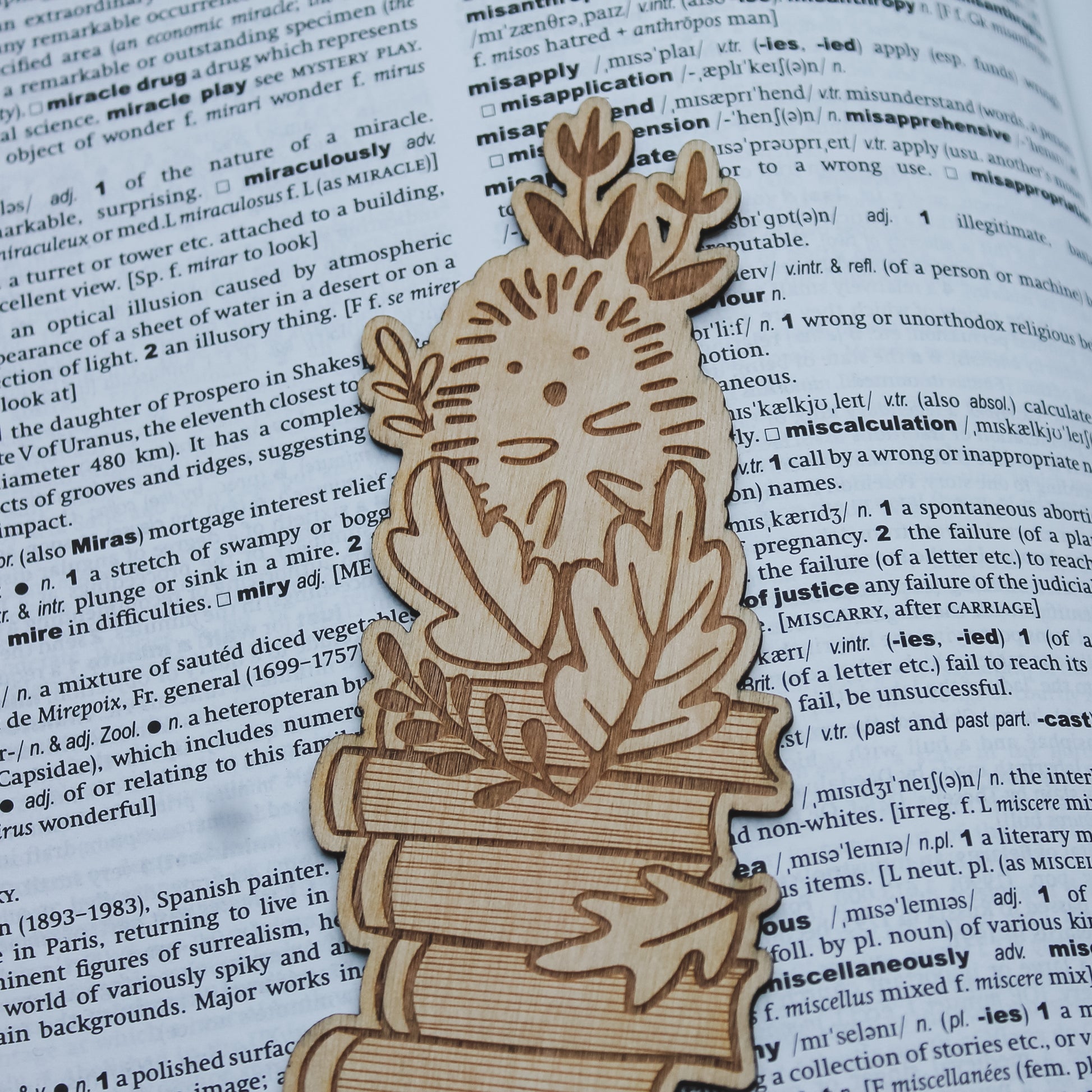 Wooden bookmark shaped like a hedgehog and autumnal leaves on an open book