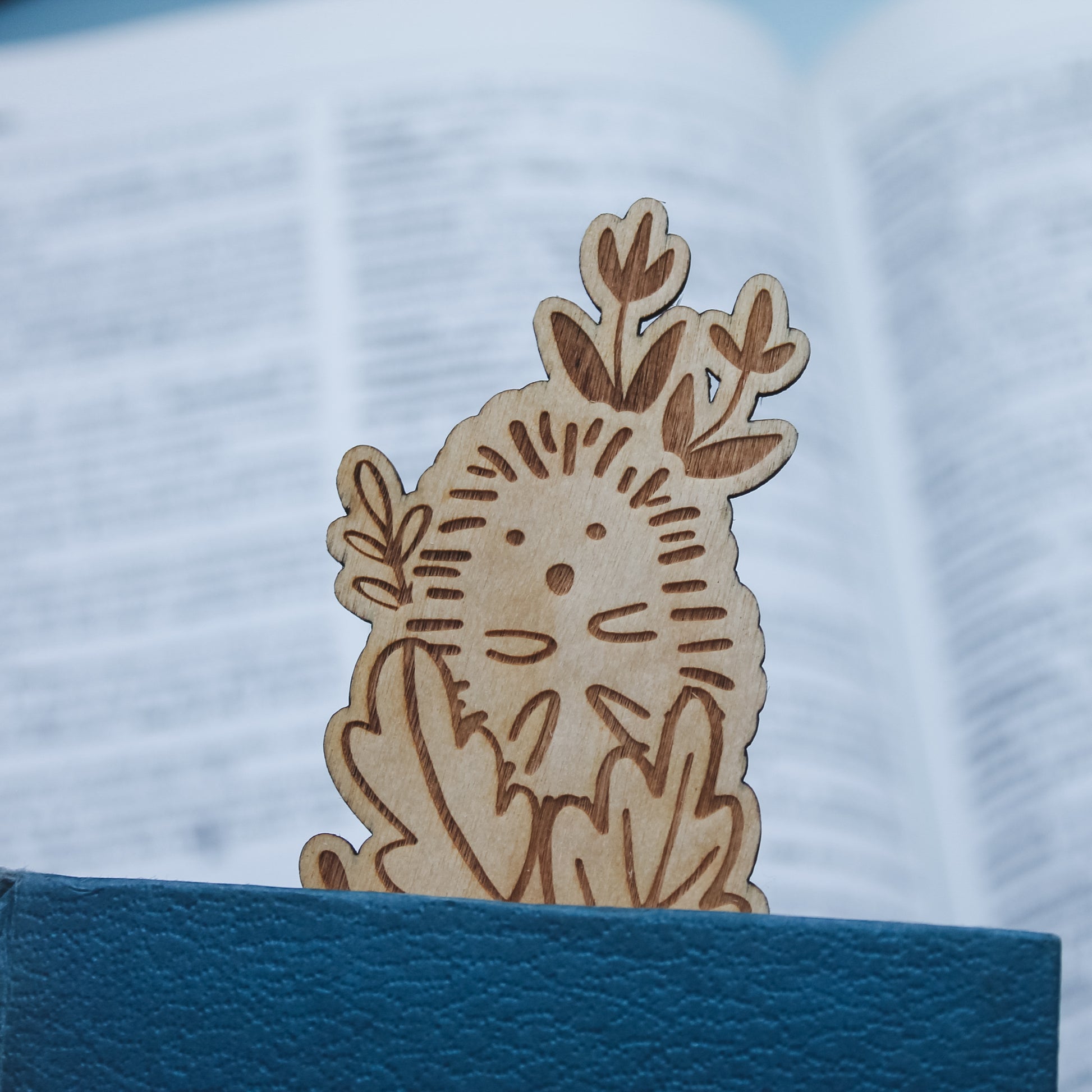 Wooden hedgehog bookmark on a peeking out of a closed book. 