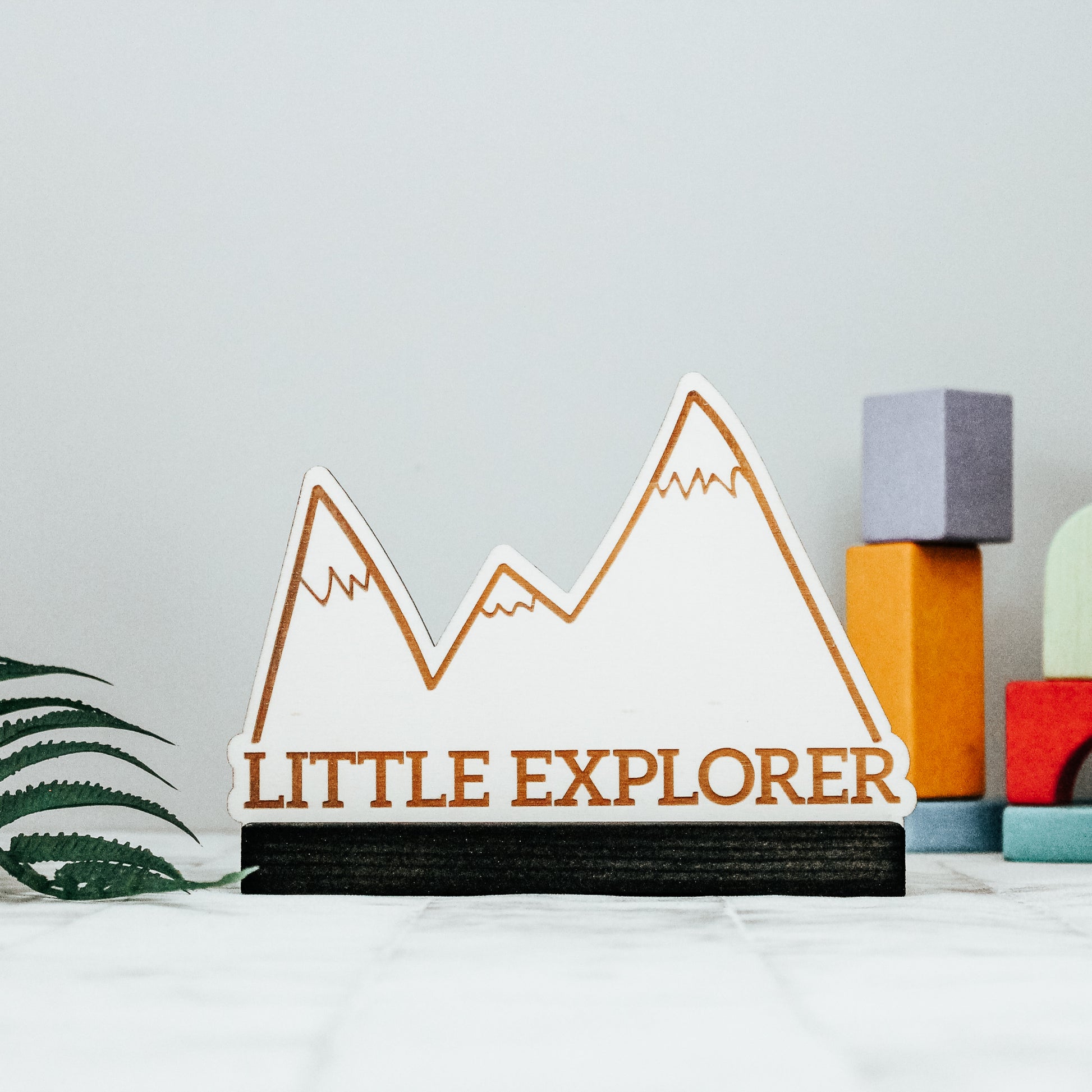 little explorer standing mountain nursery decoration, on a black wooden stained base