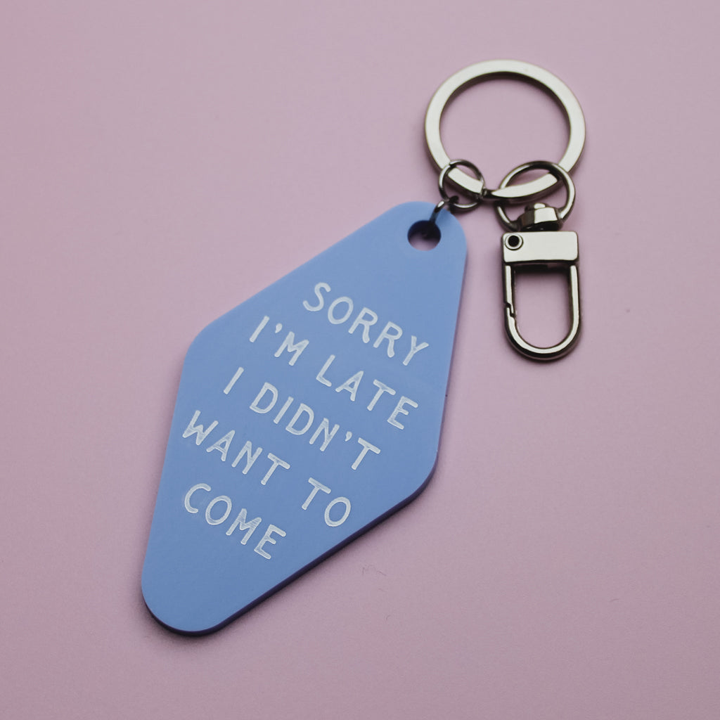 Blue Motel style keyring tag with white text saying 'sorry i'm late I didn't want to come' on a pink background