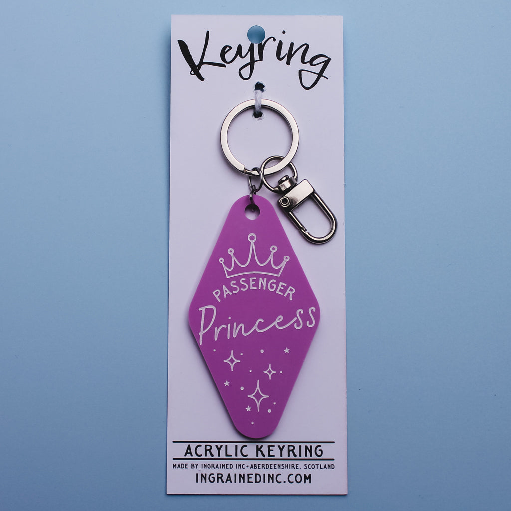 pink motel style 'Passenger Princess' keyring on a white packaging card with 'Ingrained inc' branding against a blue background
