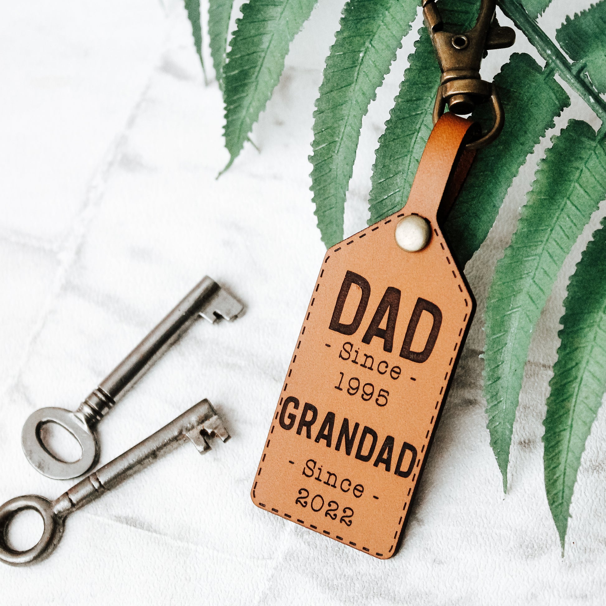 whisky colour real leather personalised keyring for grandad, engraved with custom text with the year they became and dad and grandad. Perfect gift for a first fathers day 